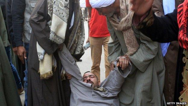 A relative of a supporter of Egyptian ousted Islamist president Mohamed Morsi is supported as he faints outside a courthouse