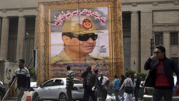 People walk past a huge portrait of Egypt's army chief, Field Marshal Abdel Fattah al-Sisi, in front of the High Court of Justice in central Cairo