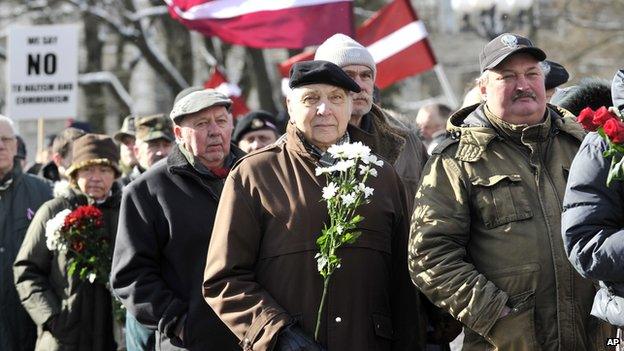 People carry Latvian flags as they march to the Freedom Monument to commemorate World War II veterans who fought in Waffen SS divisions, in Riga, Latvia, on 16 March 2014