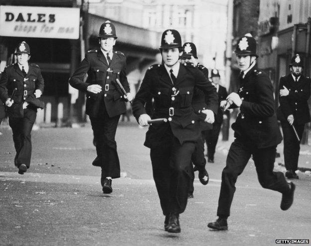 Police officers charge during the Brixton riots in 1981