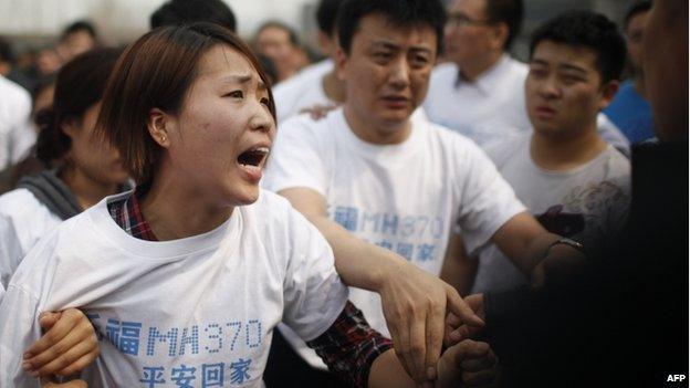 A relative of passengers on missing Malaysia Airlines flight MH370 yells at a security worker while she attends a protest outside the Malaysian embassy in Beijing on 25 March 2014.