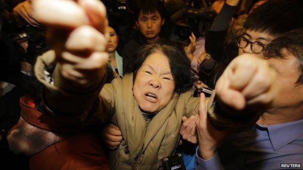 A family member of a passenger on board Malaysia Airlines MH370 shouts at journalists after watching a television broadcast of a news conference, at the Lido hotel in Beijing, on 24 March 2014