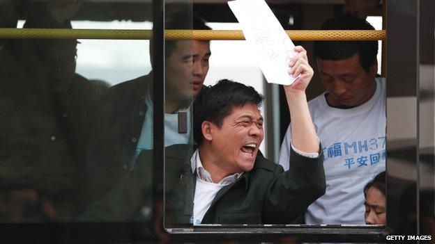 Chinese relatives of passengers on board flight MH370 sit on a bus during a protest on 25 March 2014 in Beijing, China.