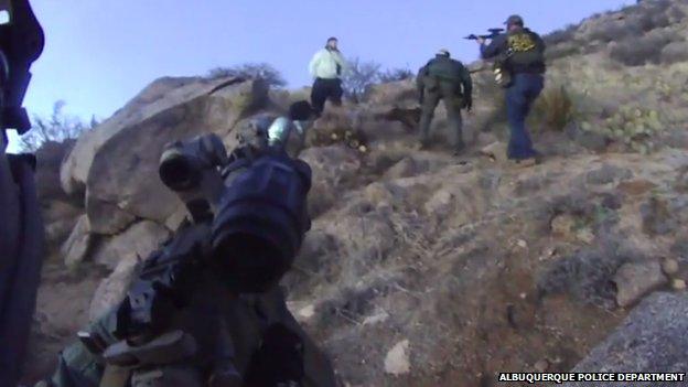 Police officers point their guns at a camper