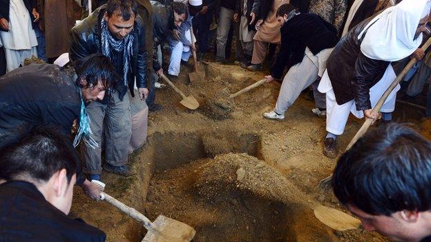 Friends and family cover the grave of one of Sardar's children with soil during the funeral. Hundreds of well-wishers turned out in the pouring rain