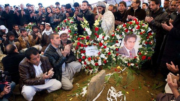 Friends and family pray at Sardar's grave during his funeral in Kabul on 23 March