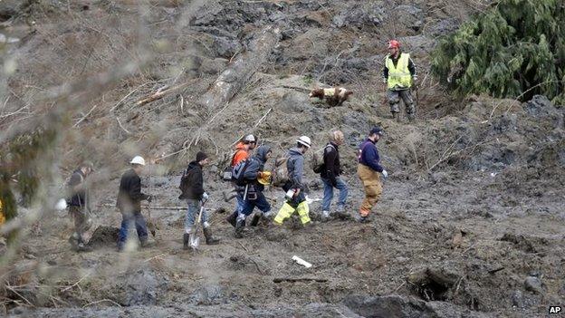 Rescuers search the mudslide field on 26 March 2014