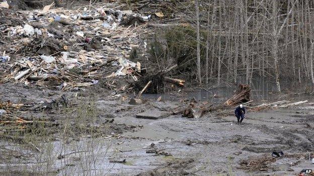 A searcher walks on the mudslide field on 26 March