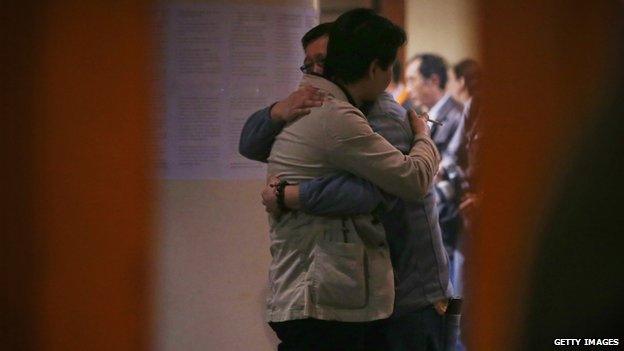 Chinese relatives of the passengers onboard Malaysia Airlines flight MH370 hug each other as they wait for the latest information in Beijing on 20 March 2014