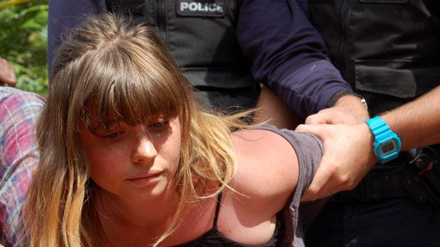 Woman having her arm held by police officer