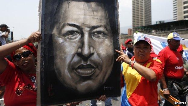 Supporters of Venezuela's late president, Hugo Chavez, hold an image of him as they take part in a rally to commemorate the 20th anniversary of Mr Chavez being freed from jail in Caracas on 26 March, 2014.