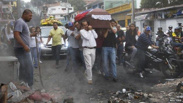 Relatives and mourners carry the coffin of Jimmy Vargas, a student who died during a protest, through a barricade during his funeral in San Cristobal on 26 February, 2014