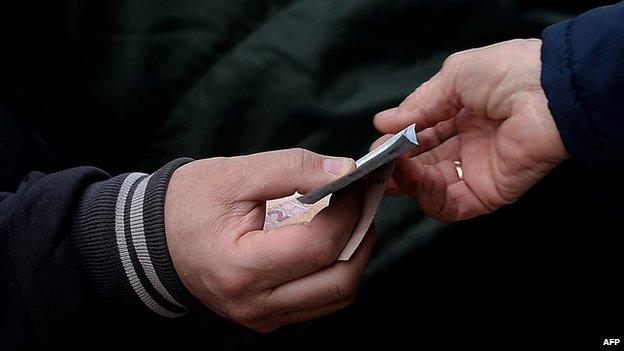 Woman pays with Ukrainian hryvnia while shopping at the main market in Crimea (file photo March 2014)