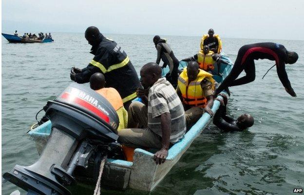 Uganda Police divers and local fishermen, on a boat, search for victims of a boat disaster on Lake Albert