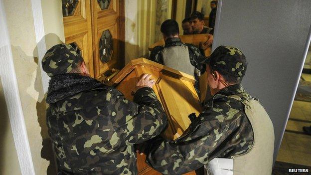 Security guards block the doors of the parliament building as activists of the Right Sector movement and their supporters gather outside the building to demand the immediate resignation of Internal Affairs Minister Arsen Avakov in Kiev on 27 March 2014.