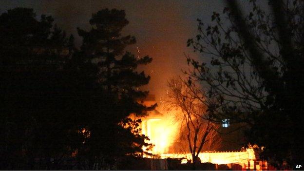 A house burns as Afghan police and special forces surround the area after suicide bombers attacked an "office of foreigners" in a neighbourhood of Kabul, Afghanistan, Friday, March 28, 2014