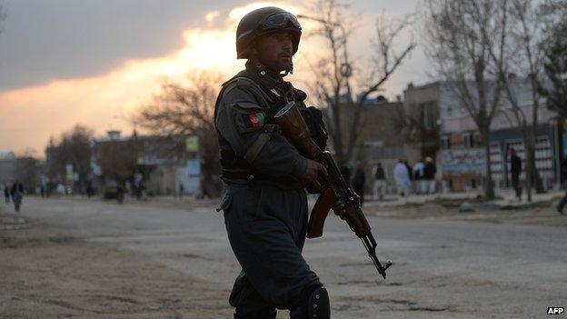 An Afghan policeman stands guard near a guesthouse attack by Taliban fighters in Kabul on March 28, 2014