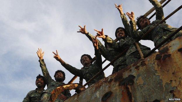 Marines wave at reporters at the disputed Second Thomas Shoal, part of the Spratly Islands, in the South China Sea on 29 March 2014