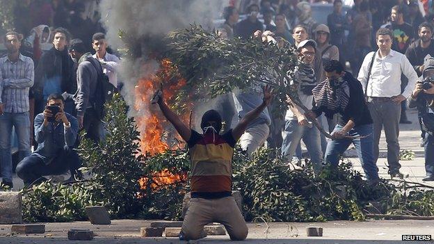 Students supporting the Muslim Brotherhood shout slogans near a bonfire in front of riot police during clashes outside near Egypt's defence ministry headquarters in Cairo on 27 March 2014.