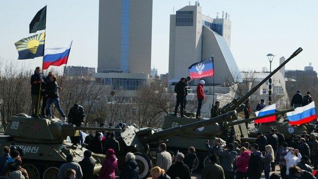 Pro-Russian demonstrators stand atop of Soviet era tanks holding Russian national flags at a World World 2 museum in Donetsk, on 30 March 2014