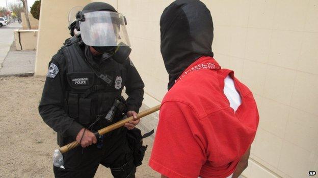 A protester faces off with an Albuquerque officer during a rally against recent police shootings in Albuquerque on Sunday 30 March 2014