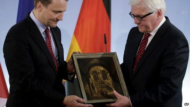 German Foreign Minister Frank-Walter Steinmeier (R) passes the "Palace Stairs" painting to his Polish counterpart Radoslaw Sikorski