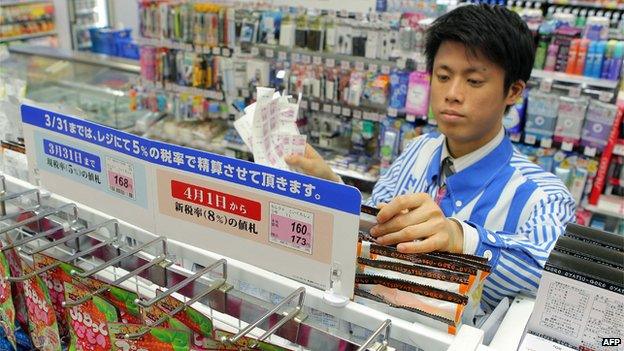 The shop manager of a convenience store updates price tags as Japan's consumption tax raises from five percent to eight percent in Tokyo on 31 March 2014