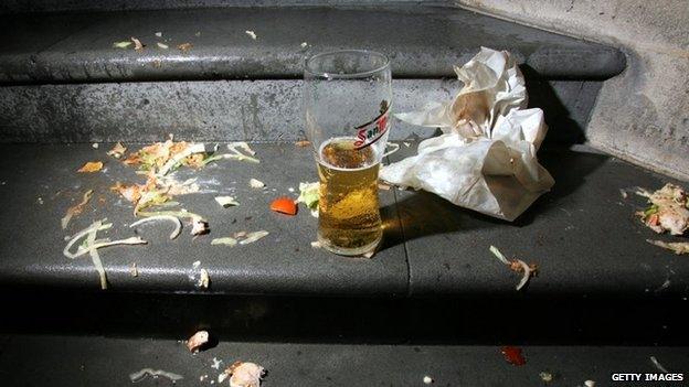 Discarded takeaway wrapper with a pint of lager, left on steps