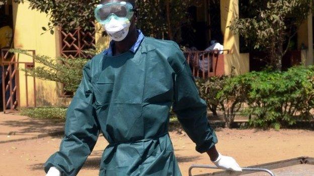 A health worker in light protective gear walks on 31 March 2014 in the yard of the isolation ward of the Donka hospital in Conakry, Guinea