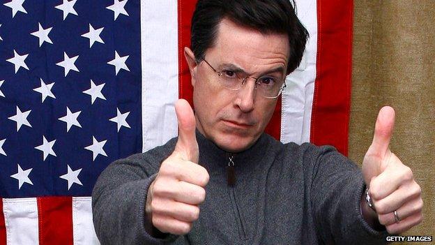 Stephen Colbert gives a thumbs-up in front of a US flag