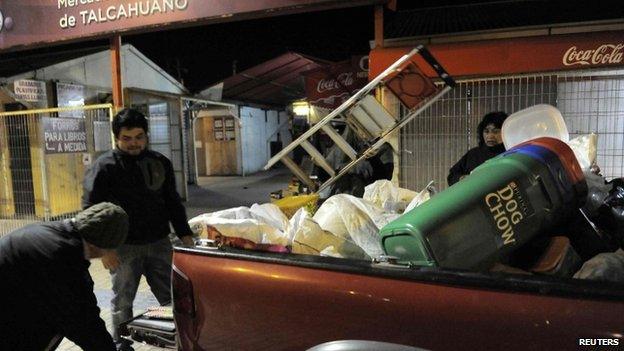 Residents take their belongings to higher ground after a Tsunami alarm at Talcahuano city, south of Santiago