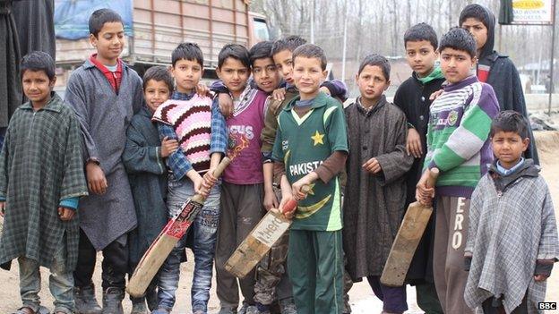 Children playing cricket stop to pose for a picture in the streets of Kashmir