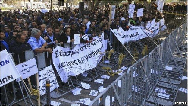 Demonstrators hold signs and banners outside Cyprus’s parliament as they protest plans by the government in Nicosia 27/02/14.