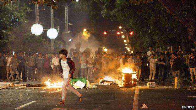 Demonstrators set fire to trash cans, as they protest against a chemical plant project, on a street in Maoming, Guangdong province, 1 April 2014