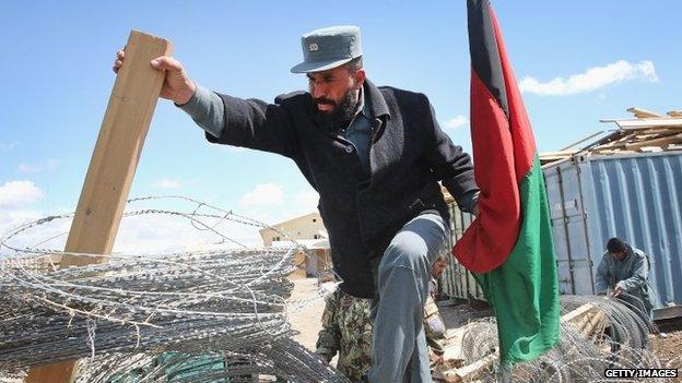 An Afghan National Police (ANP) officer loads concertina wire, which will be used to secure polling places ahead of presidential elections