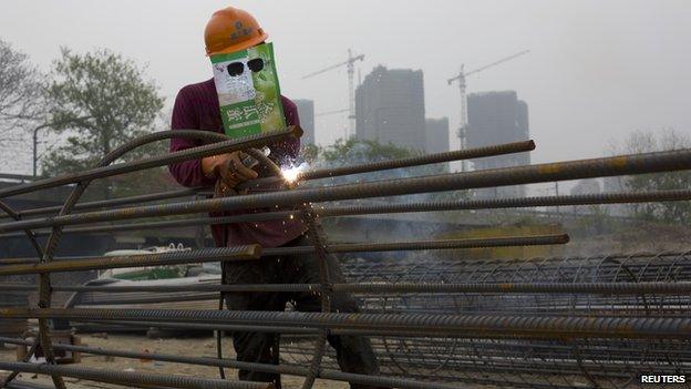 A labourer, wearing an improvised protective mask, welds steel bars at a residential construction site in Quzhou, Zhejiang province on 3 April 2014.