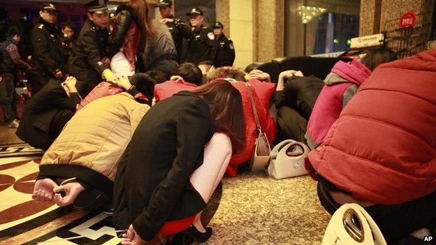 Detained suspects gathered in a lobby during an anti-prostitution raid at a hotel in Dongguan in south China's Guangdong province on 9 February 2014