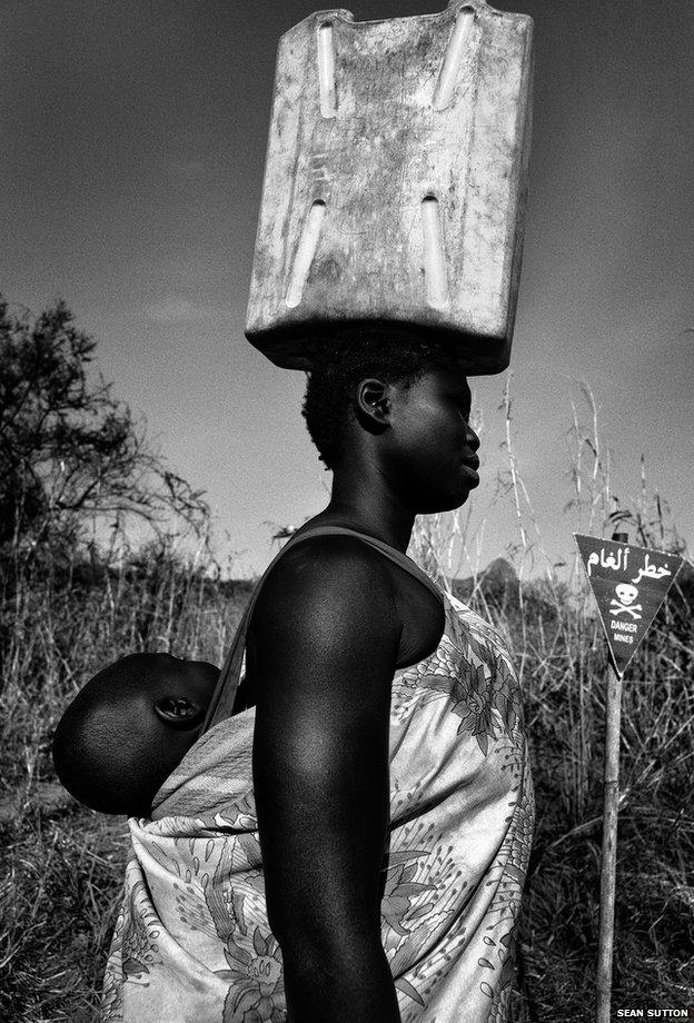 Maria walks through a minefield to get water from a nearby stream every day, South Sudan's Central Equatoria region, 2013