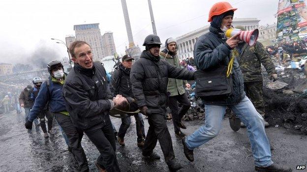 Anti-government protesters carry a wounded demonstrator in Kiev. Photo: 20 February 2014