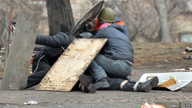 Anti-government protesters shield a wounded demonstrator in Kiev. Photo: 20 February 2014