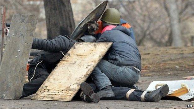 Anti-government protesters shield a wounded demonstrator in Kiev. Photo: 20 February 2014