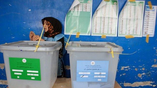 An Afghan employee of the Independent Elections Commission waits for voters standing beside ballot boxes at a polling station in Mazar-i-Sharif