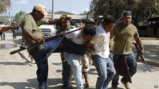 A community policeman kicks a man suspected of participating in an ambush against them near the town of La Concepcion on 4 April, 2014