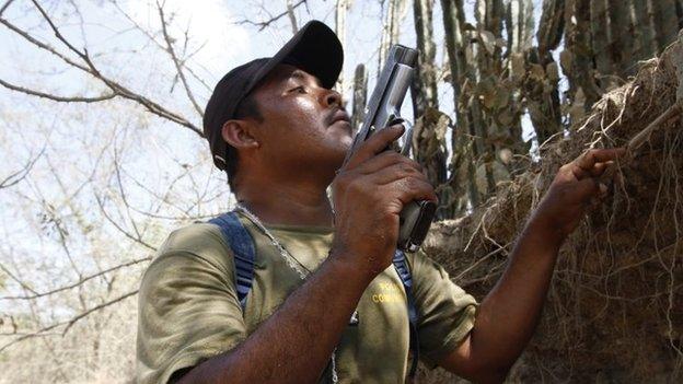 A community policeman holds up his gun while taking cover after being ambushed by gunmen near the town of La Concepcion on 4 April, 2014