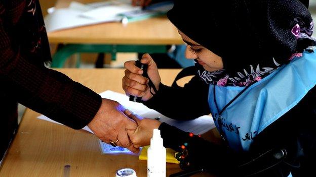 An election worker uses a scanner to check a voter's inked finger