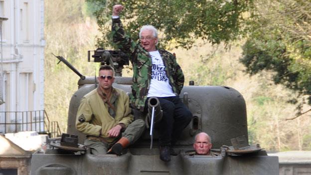 Tony Miles (centre) waves to bemused residents of Caledonia Place