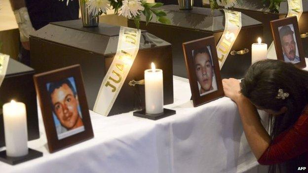 A woman cries next to the funerary urn with the remains of her relative disappeared during the Colombian civil war, in a ceremony in Medellin on 21 March, 2014