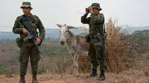 Police officers stand guard during a government's land restitution process to farmers victims of forced displacement by armed conflict, on a farm in a rural area of Valencia, Cordoba department, Colombia on March 29, 2014