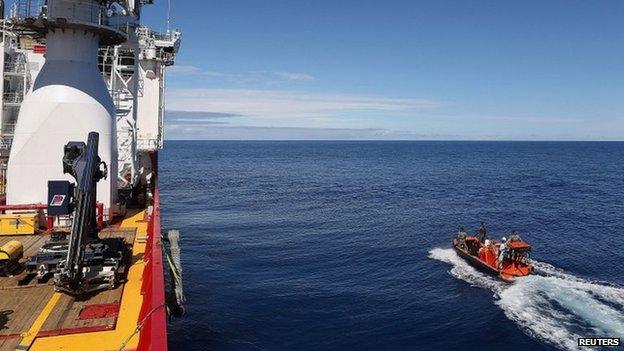 Crew members are seen aboard a fast response craft (R) from the Australian Defence Vessel Ocean Shield (L) as they continue to search for debris of MH370 in the southern Indian Ocean on 8 April 2014