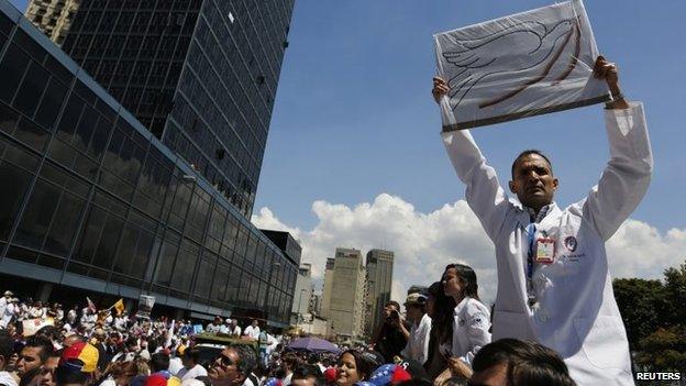 An anti-government doctor holds up a placard with a picture of a peace dove during a march to demand medical supplies for hospitals in Caracas on 10 March, 2014